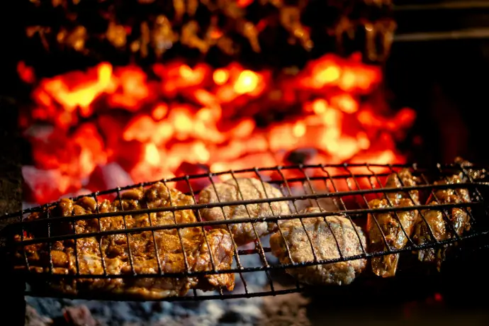 Meat grilling over glowing hot coals